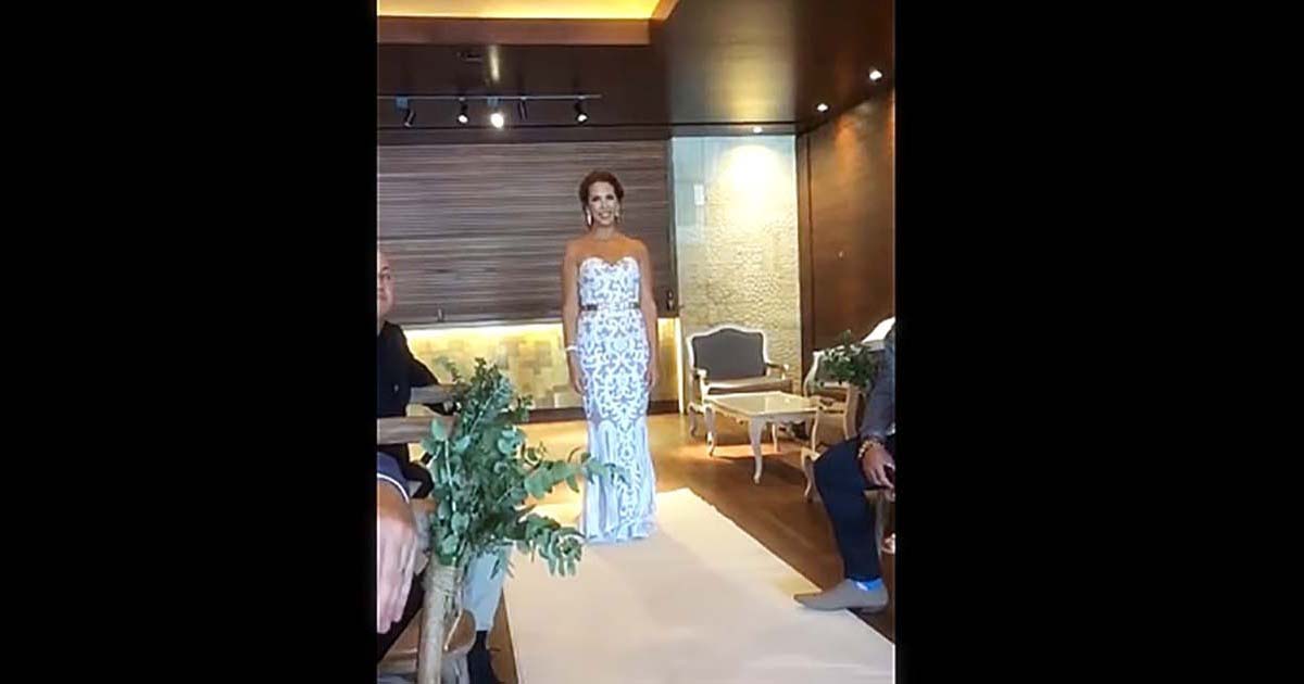 Bride walks in, but suddenly stops. Makes quick movement with arms that forces groom to tears