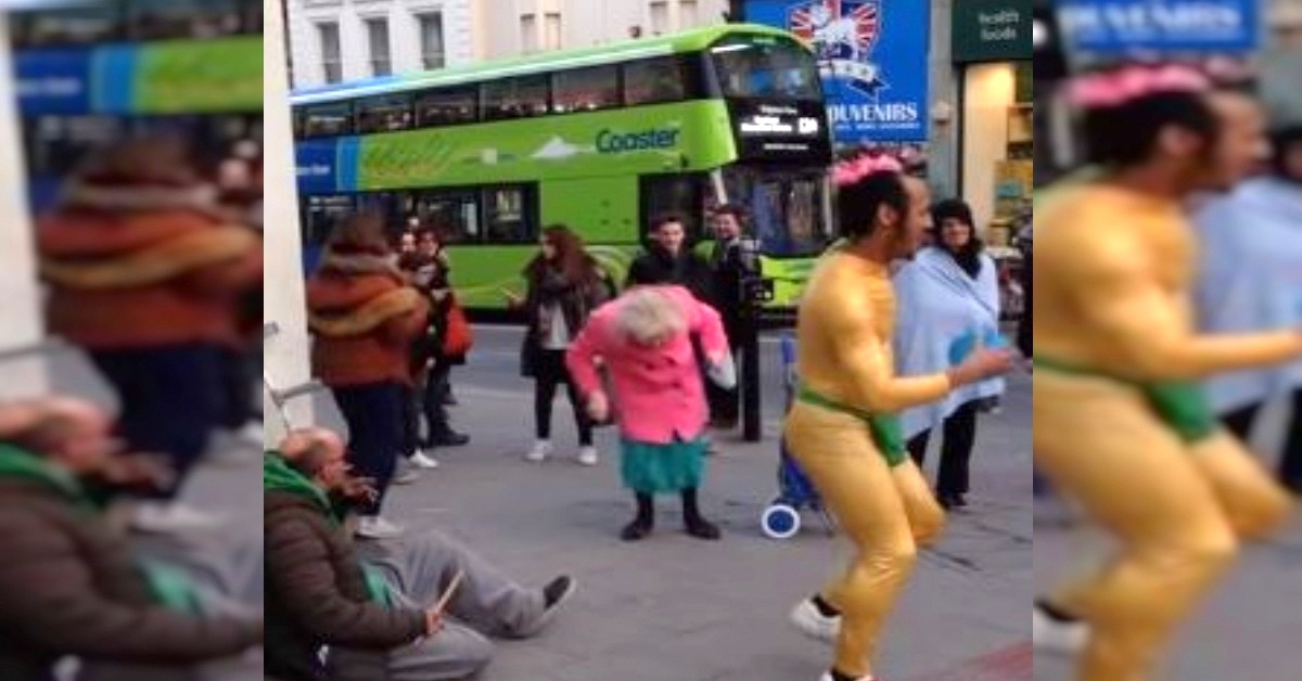 Street Performer Gets Crowd’s Attention, But It’s The Woman In Pink Coat Who Steals The Show